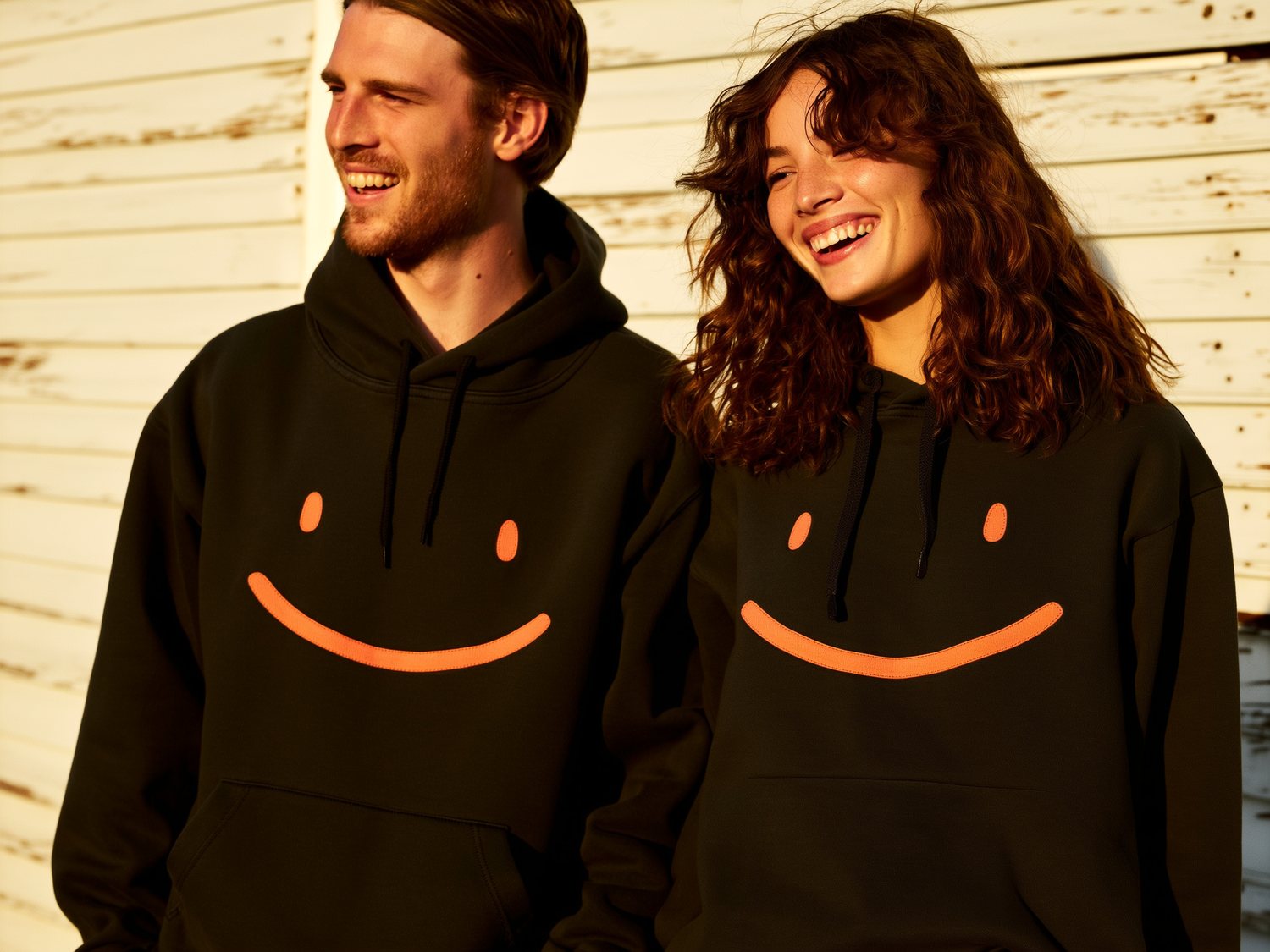 Pareja con hoodies negros y la sonrisa terracota, luz dorada